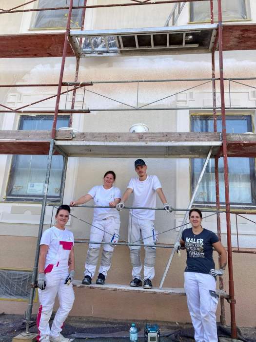 Professional painter rolling fresh white paint on a living room wall, modern Austrian home